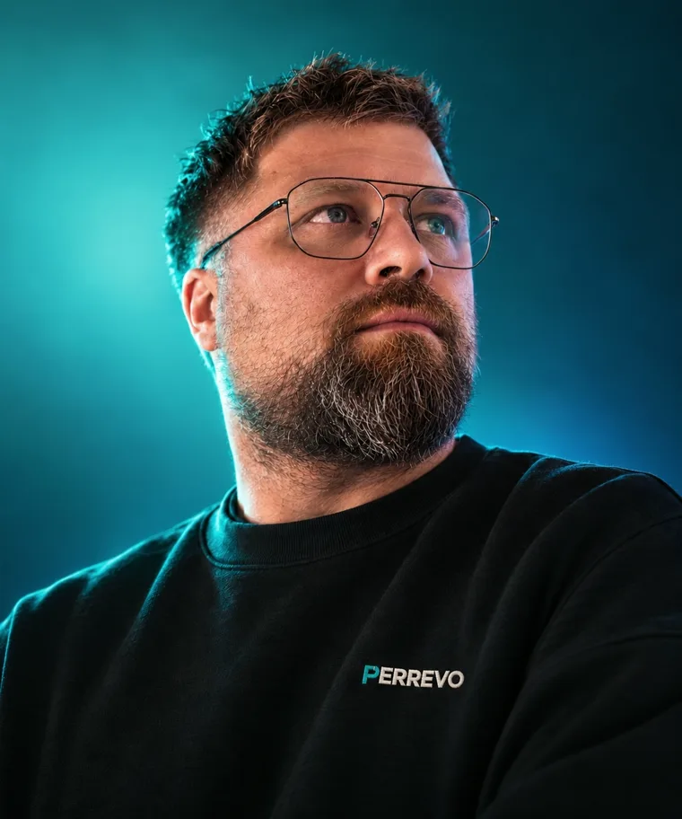 Daniel Perret, Inhaber von Perrevo, im Perrevo-Pullover vor türkisem Hintergrund